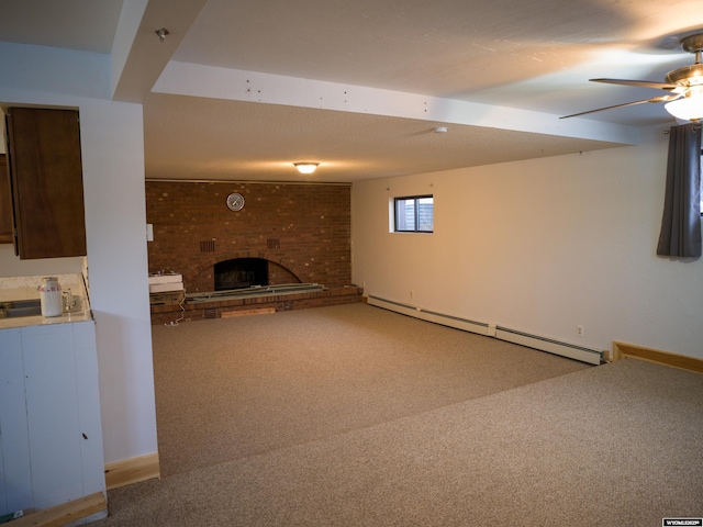 basement with carpet floors, ceiling fan, a brick fireplace, and a baseboard radiator