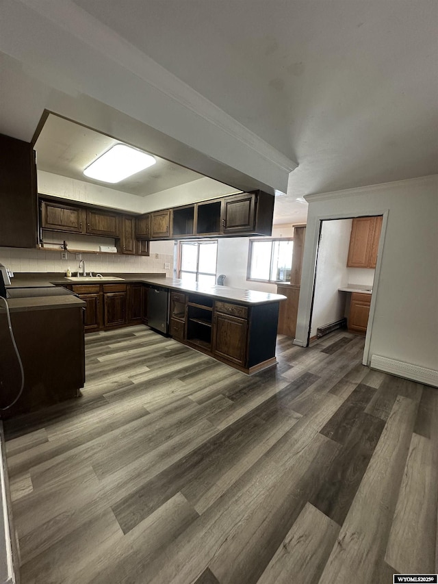 kitchen featuring stainless steel dishwasher, wood-type flooring, kitchen peninsula, sink, and dark brown cabinetry