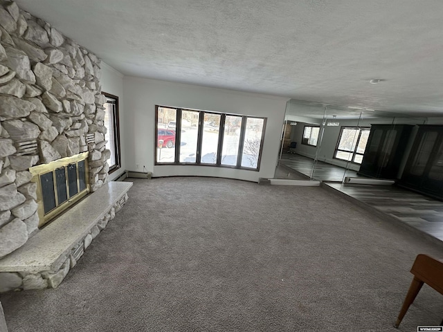 unfurnished living room featuring a textured ceiling, a stone fireplace, and dark colored carpet