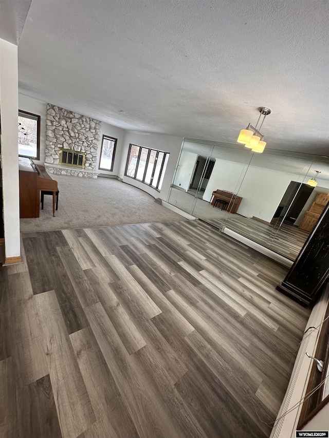 unfurnished living room with a healthy amount of sunlight, a fireplace, a textured ceiling, and carpet flooring