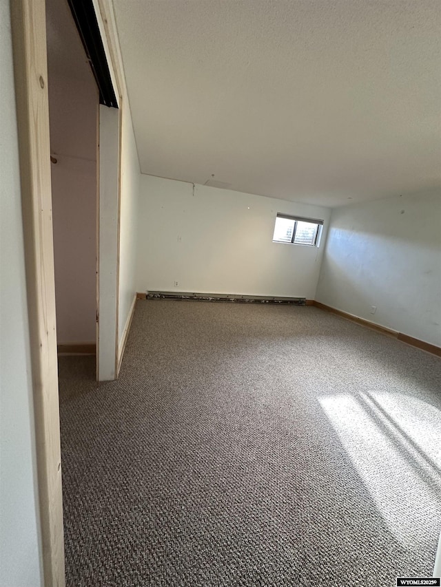 basement featuring a baseboard heating unit and dark colored carpet