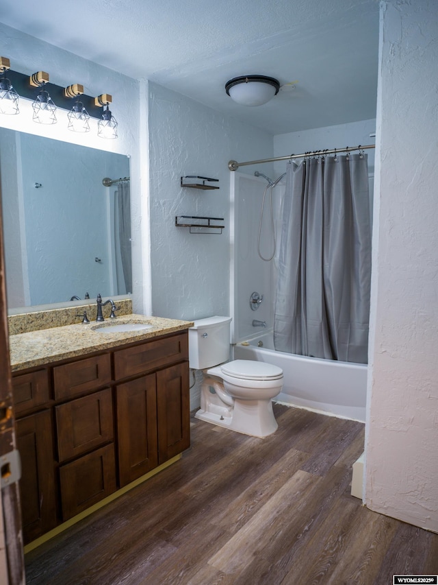 full bathroom featuring toilet, vanity, shower / bath combo, hardwood / wood-style flooring, and a textured ceiling