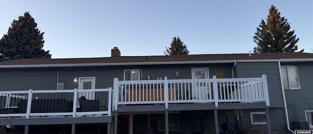 back of house with a deck, a chimney, and cooling unit