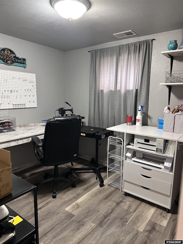 office space featuring a textured ceiling, visible vents, and wood finished floors