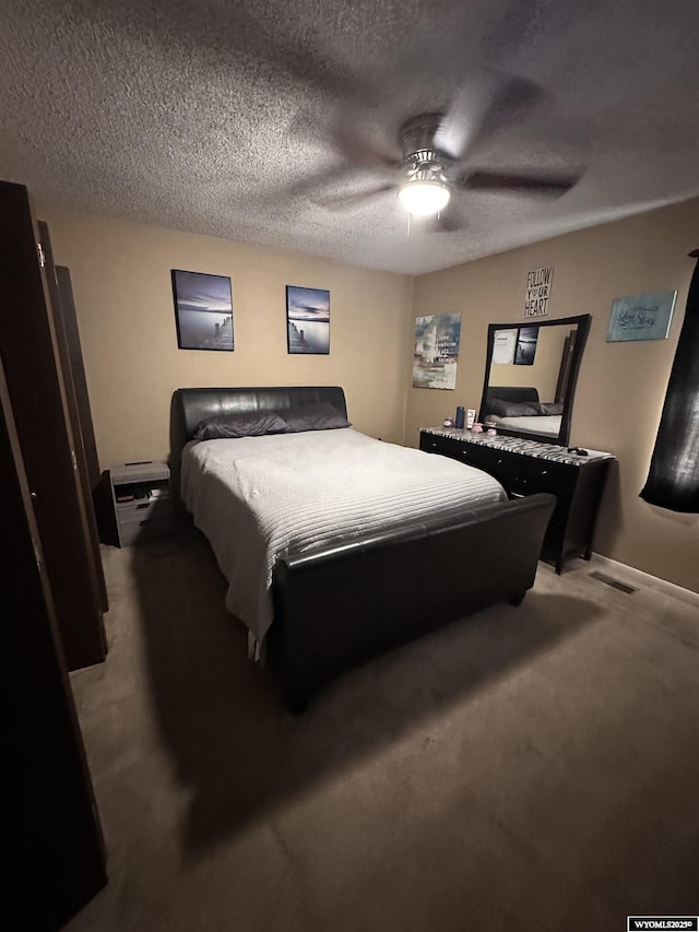 bedroom featuring carpet, visible vents, ceiling fan, and a textured ceiling