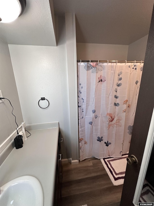 full bathroom with a shower with curtain, a sink, and wood finished floors