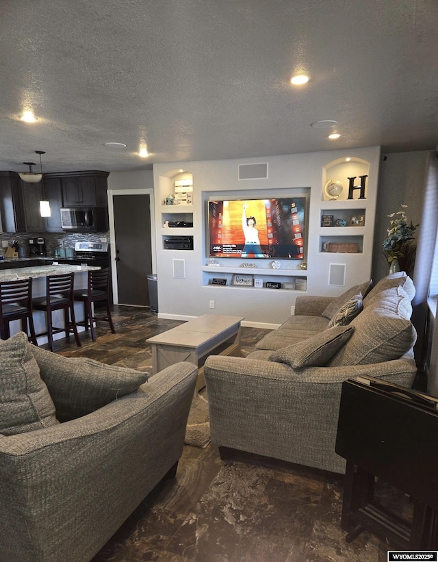 living room featuring built in shelves, visible vents, and a textured ceiling