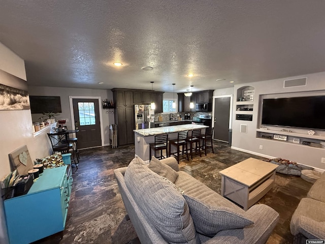 living room with baseboards, built in shelves, visible vents, and a textured ceiling