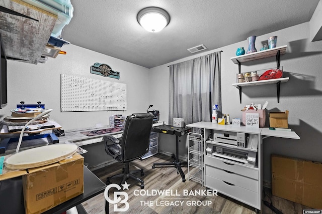 office featuring visible vents, a textured ceiling, and wood finished floors