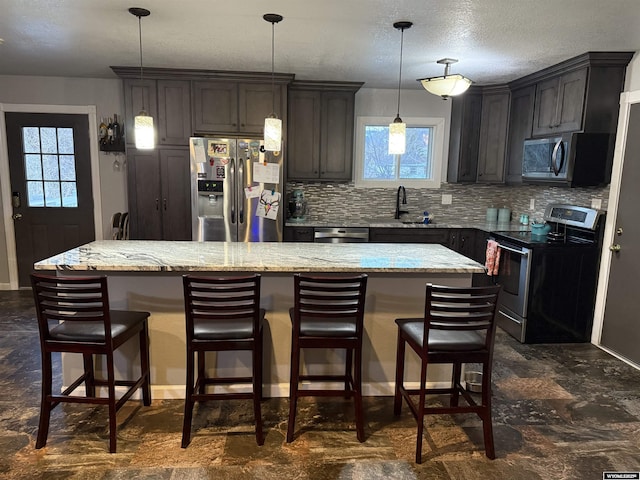 kitchen with appliances with stainless steel finishes, a center island, a healthy amount of sunlight, and tasteful backsplash