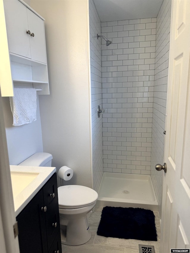 bathroom with vanity, tiled shower, and toilet