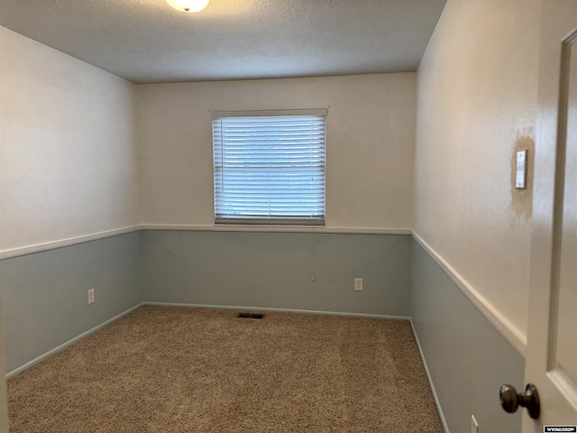 carpeted empty room with a textured ceiling