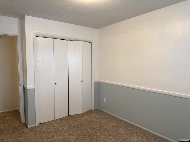 unfurnished bedroom with a closet, light carpet, and a textured ceiling