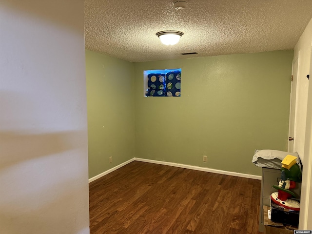 spare room with a textured ceiling and dark hardwood / wood-style flooring