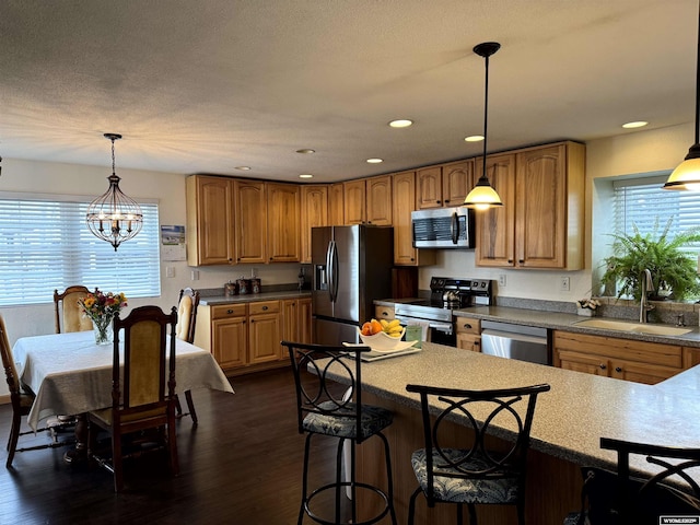 kitchen featuring pendant lighting, sink, appliances with stainless steel finishes, dark hardwood / wood-style floors, and a chandelier