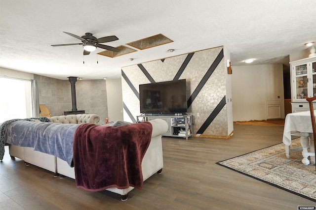 living room featuring hardwood / wood-style floors, ceiling fan, and a wood stove