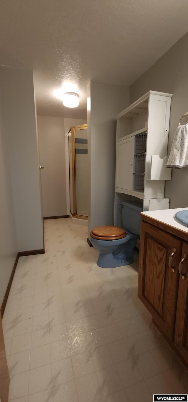 bathroom featuring a textured ceiling, walk in shower, vanity, and toilet