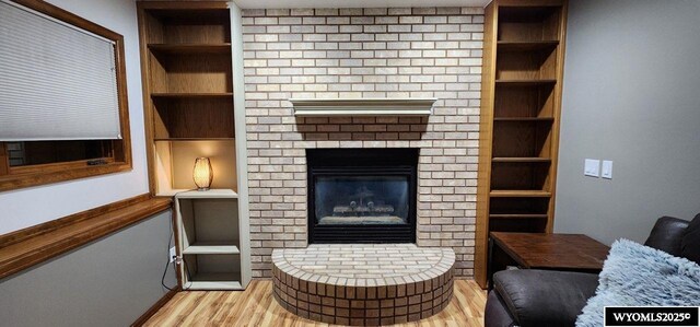 living room featuring light hardwood / wood-style floors, a fireplace, and built in shelves