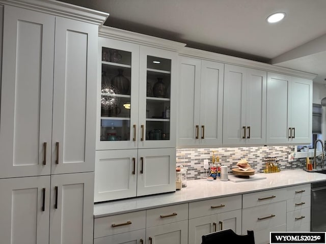 bar featuring white cabinets, backsplash, and black dishwasher