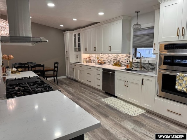 kitchen with decorative light fixtures, white cabinetry, dishwashing machine, and island range hood