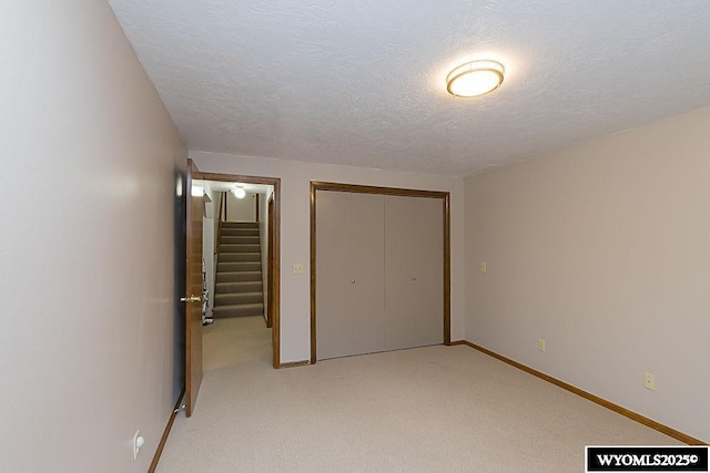 unfurnished bedroom with light carpet, a closet, and a textured ceiling