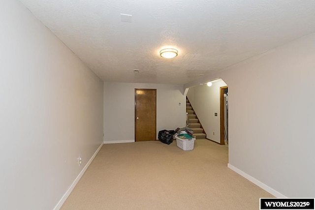 basement featuring light carpet and a textured ceiling