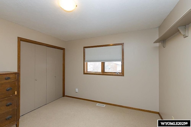 unfurnished bedroom with a closet and light colored carpet