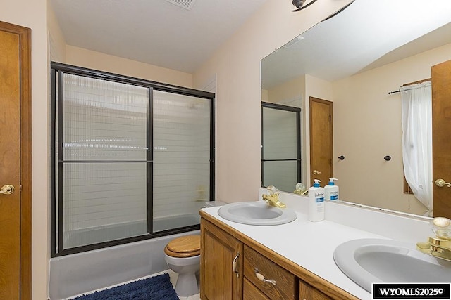 full bathroom featuring toilet, enclosed tub / shower combo, and vanity