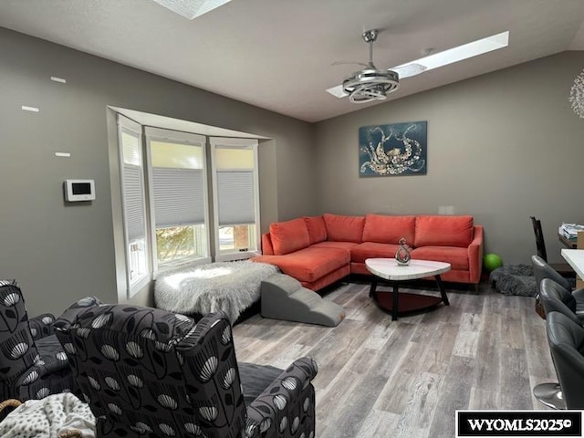 living room featuring wood-type flooring and lofted ceiling with skylight