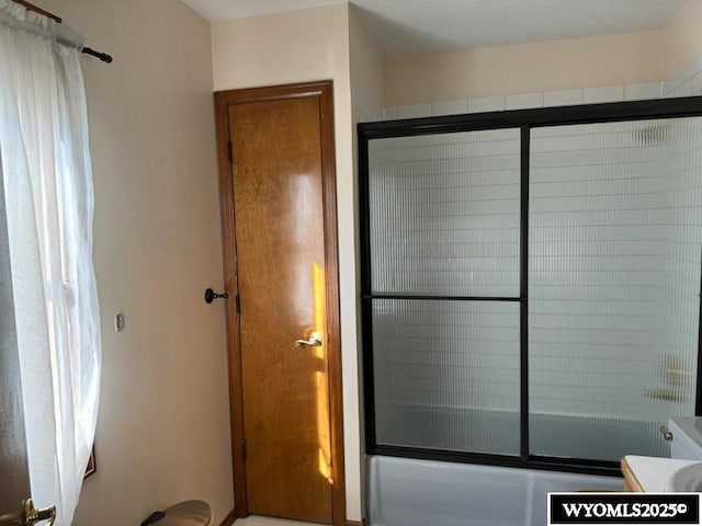 bathroom with combined bath / shower with glass door and vanity