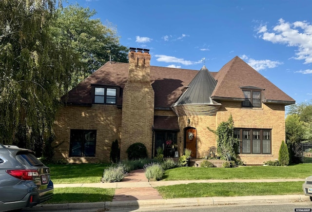 2401 Main St, Torrington, WY 82240 - tudor-style house with a front yard, brick siding, a chimney, and a standing seam roof