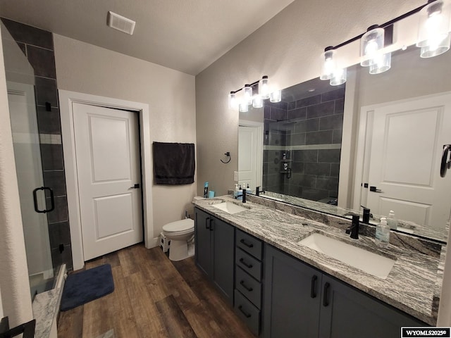 bathroom featuring hardwood / wood-style flooring, vanity, toilet, and a shower with door