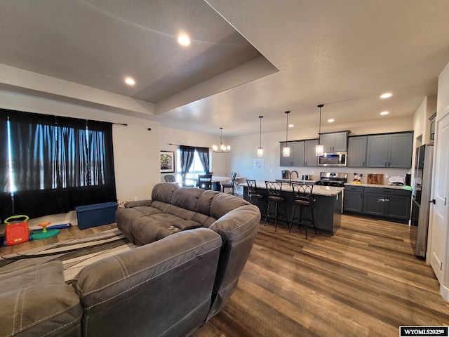 living room with a raised ceiling, a chandelier, and dark hardwood / wood-style flooring