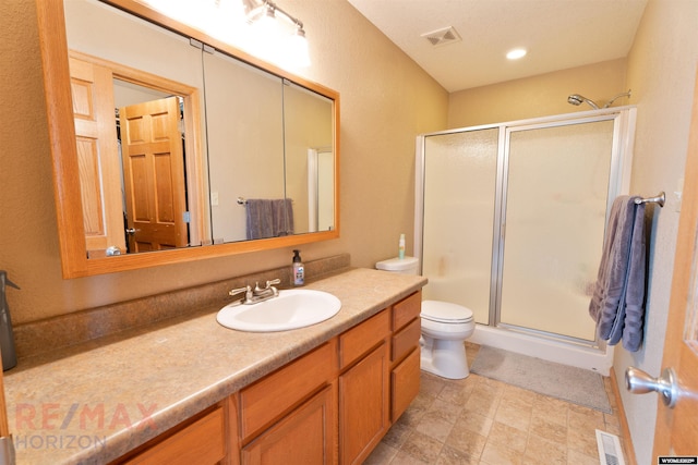 bathroom with vanity, toilet, and a shower with shower door