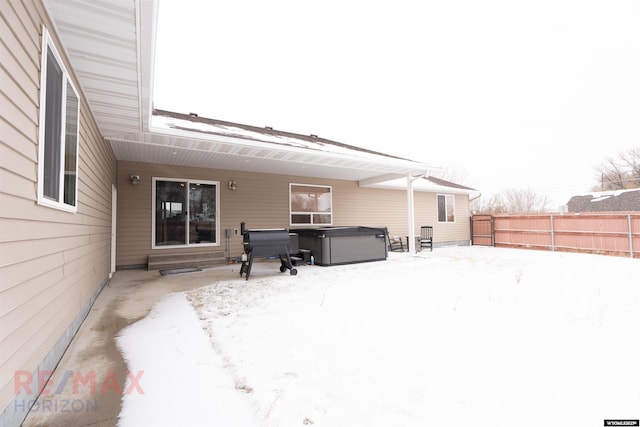 snow covered house featuring a hot tub