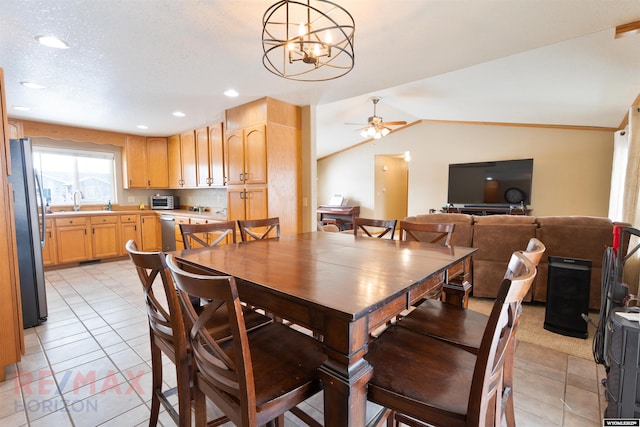 dining area featuring lofted ceiling, ceiling fan with notable chandelier, and light tile patterned floors