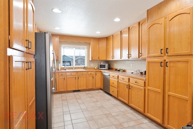 kitchen featuring stainless steel appliances, sink, a textured ceiling, and light tile patterned floors