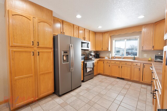 kitchen featuring light tile patterned flooring, appliances with stainless steel finishes, and a textured ceiling