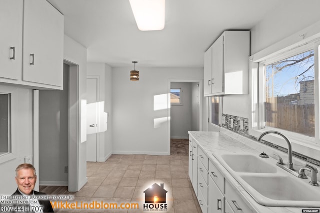 kitchen featuring plenty of natural light, pendant lighting, white cabinets, and sink