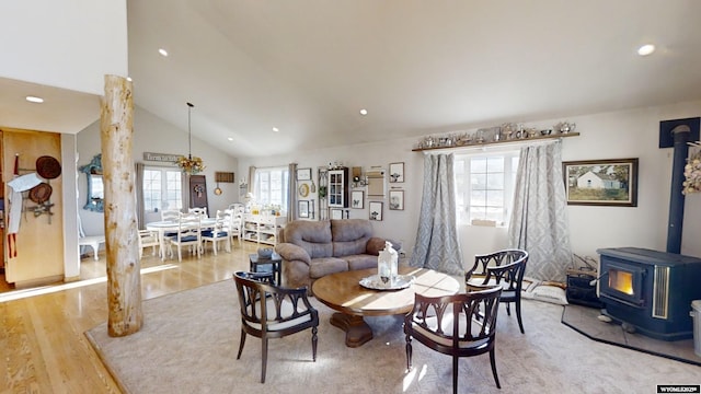 living room featuring a wood stove, lofted ceiling, and light wood-type flooring