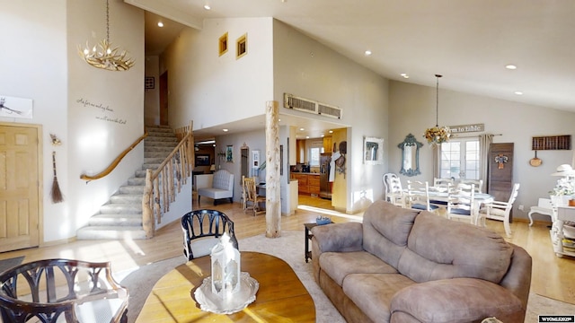 living room featuring high vaulted ceiling, a notable chandelier, and light hardwood / wood-style flooring