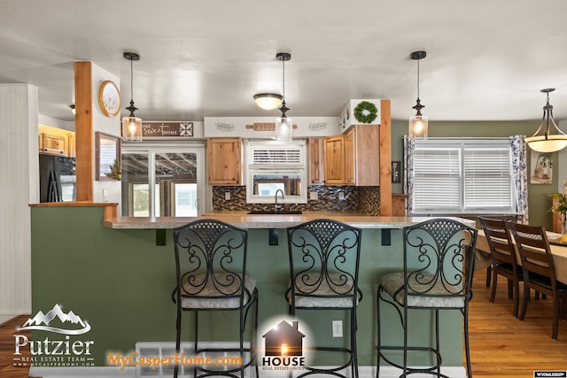 kitchen featuring decorative light fixtures, black refrigerator, plenty of natural light, and sink