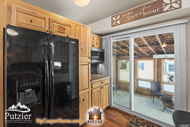 kitchen with light brown cabinetry, dark wood-type flooring, and black fridge with ice dispenser