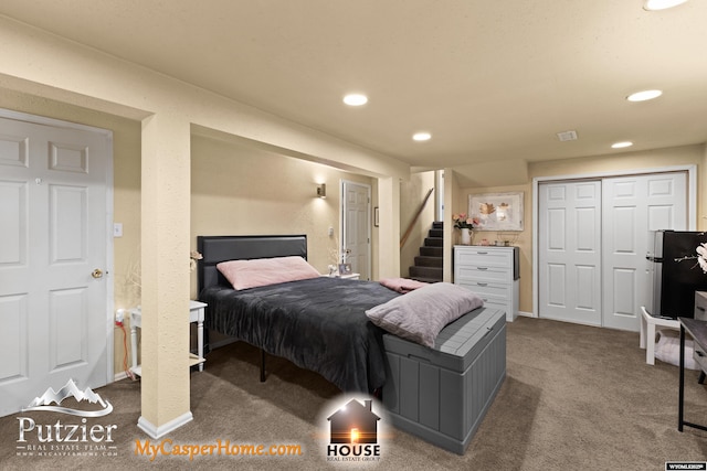 carpeted bedroom featuring a closet and stainless steel refrigerator