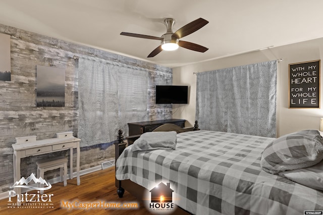 bedroom with ceiling fan, wood walls, and hardwood / wood-style floors