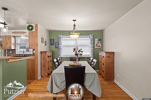 dining space with light wood-type flooring, a wealth of natural light, and sink