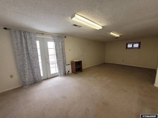 carpeted empty room featuring a textured ceiling and french doors