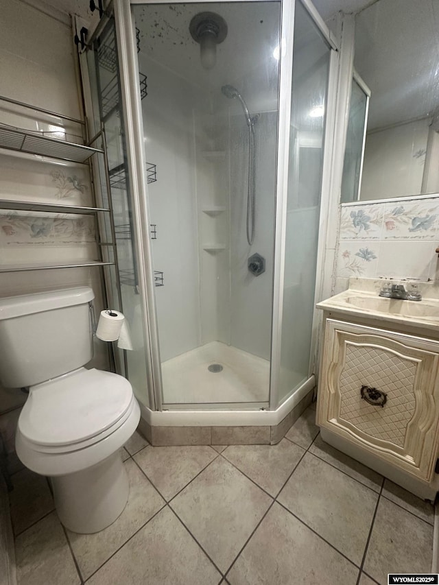 bathroom featuring toilet, tile patterned flooring, walk in shower, and vanity