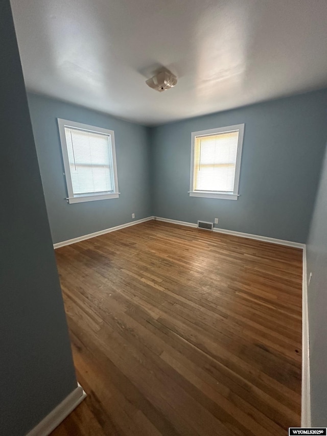 unfurnished room featuring dark hardwood / wood-style floors and a healthy amount of sunlight