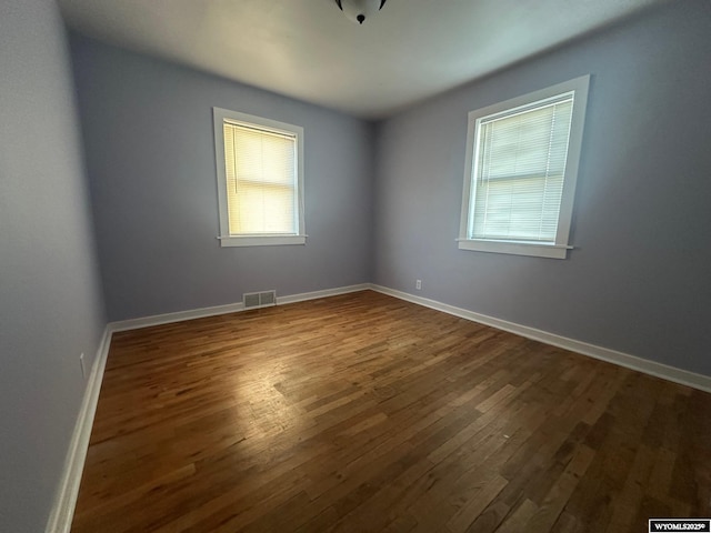 empty room with hardwood / wood-style flooring and plenty of natural light